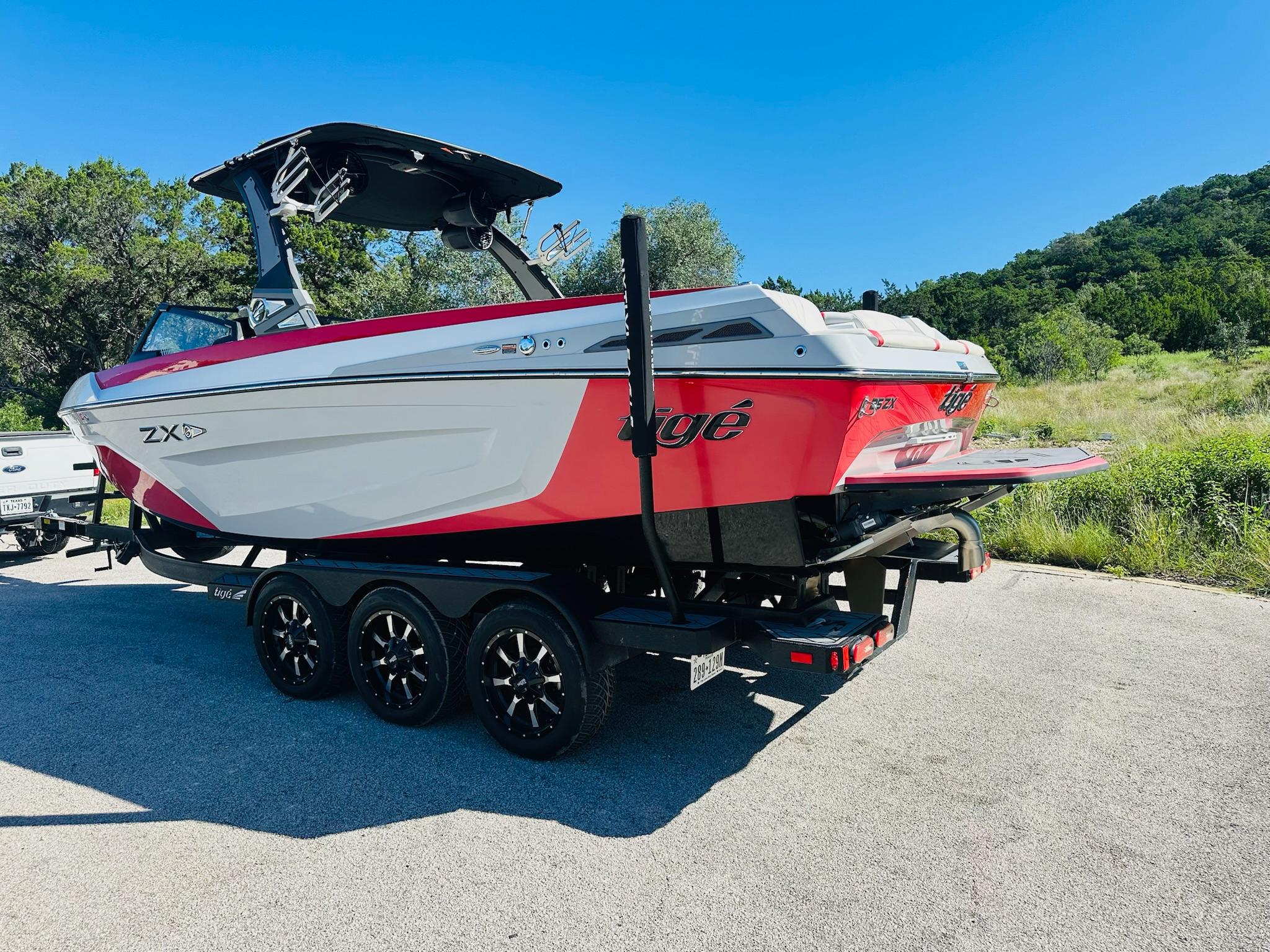 Slide: The Image of 2020 Tigé 25ZX boat on trailer, red and white design, parked outdoors. - 10