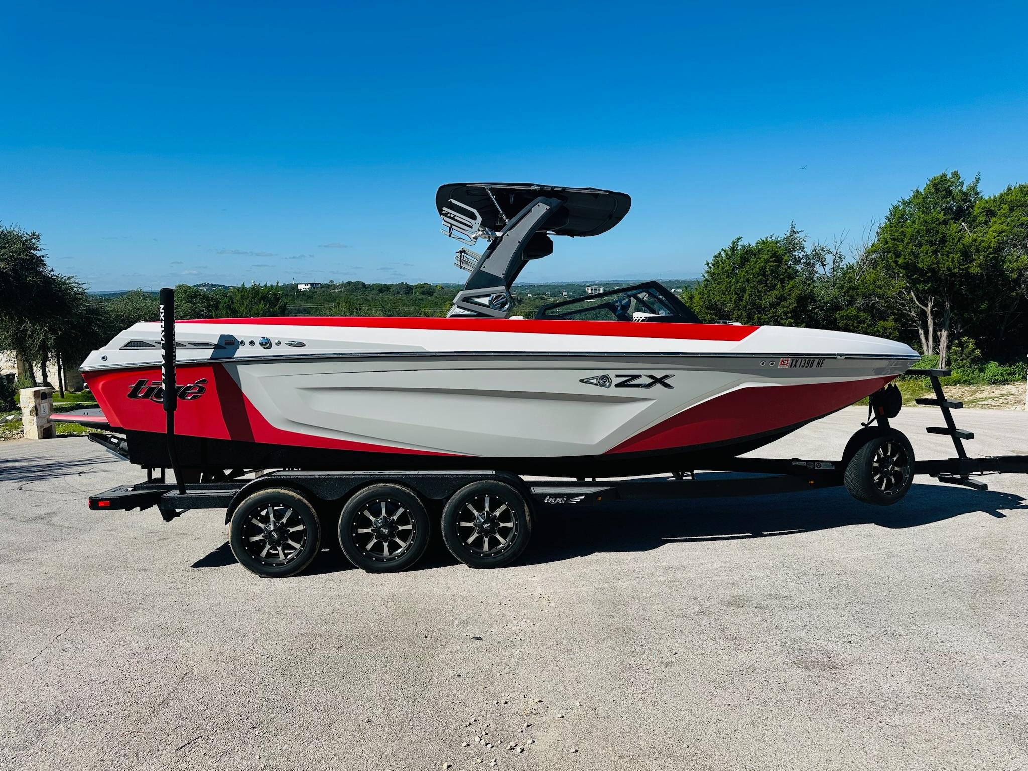 Slide: The Image of 2020 Tigé 25ZX boat on trailer, red and white design, parked outdoors. - 6
