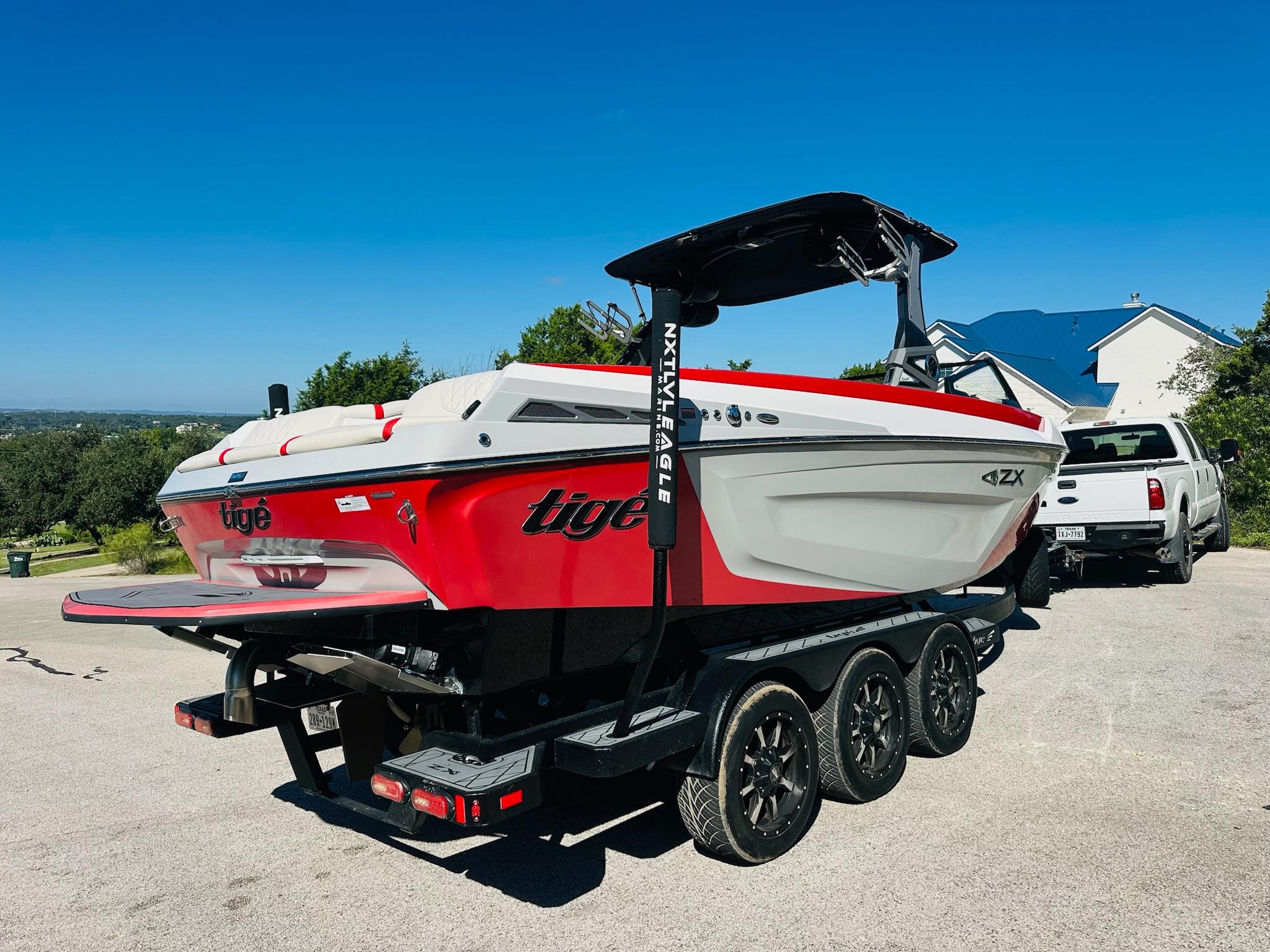 Slide: The Image of 2020 Tigé 25ZX boat on trailer, red and white design, parked outdoors. - 7