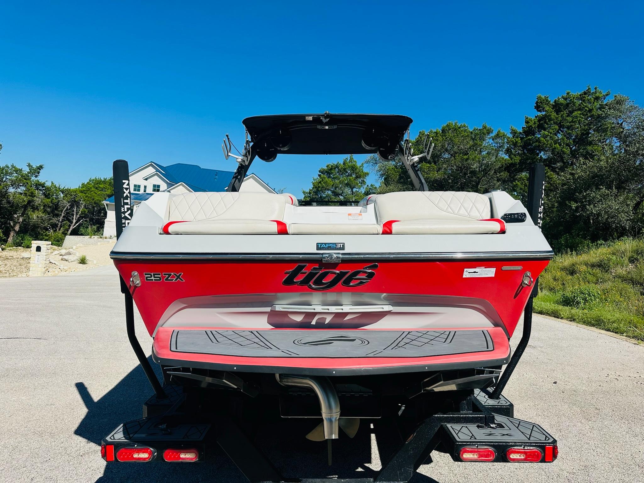 Slide: The Image of 2020 Tigé 25ZX boat, red exterior, parked on a sunny day. - 9