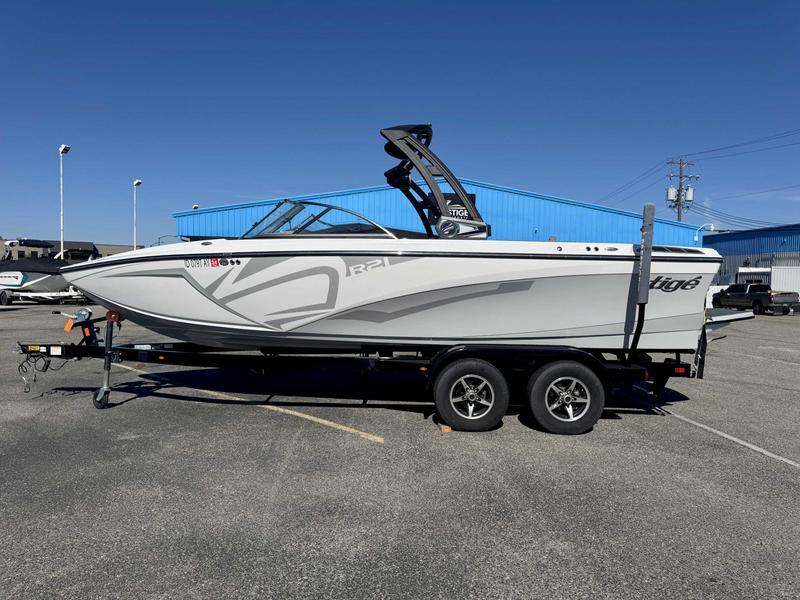 Slide: The Image of 2019 Tigé R21 boat on trailer, parked in a lot with blue building background. - 1