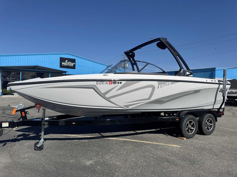 Slide: The Image of 2019 Tigé R21 boat on trailer outside a blue building under clear sky. - 3