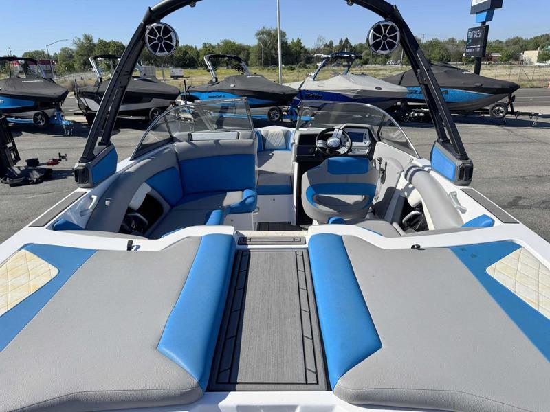 Slide: The Image of 2019 Tigé R21 boat interior with blue and gray seating, parked outdoors. - 9