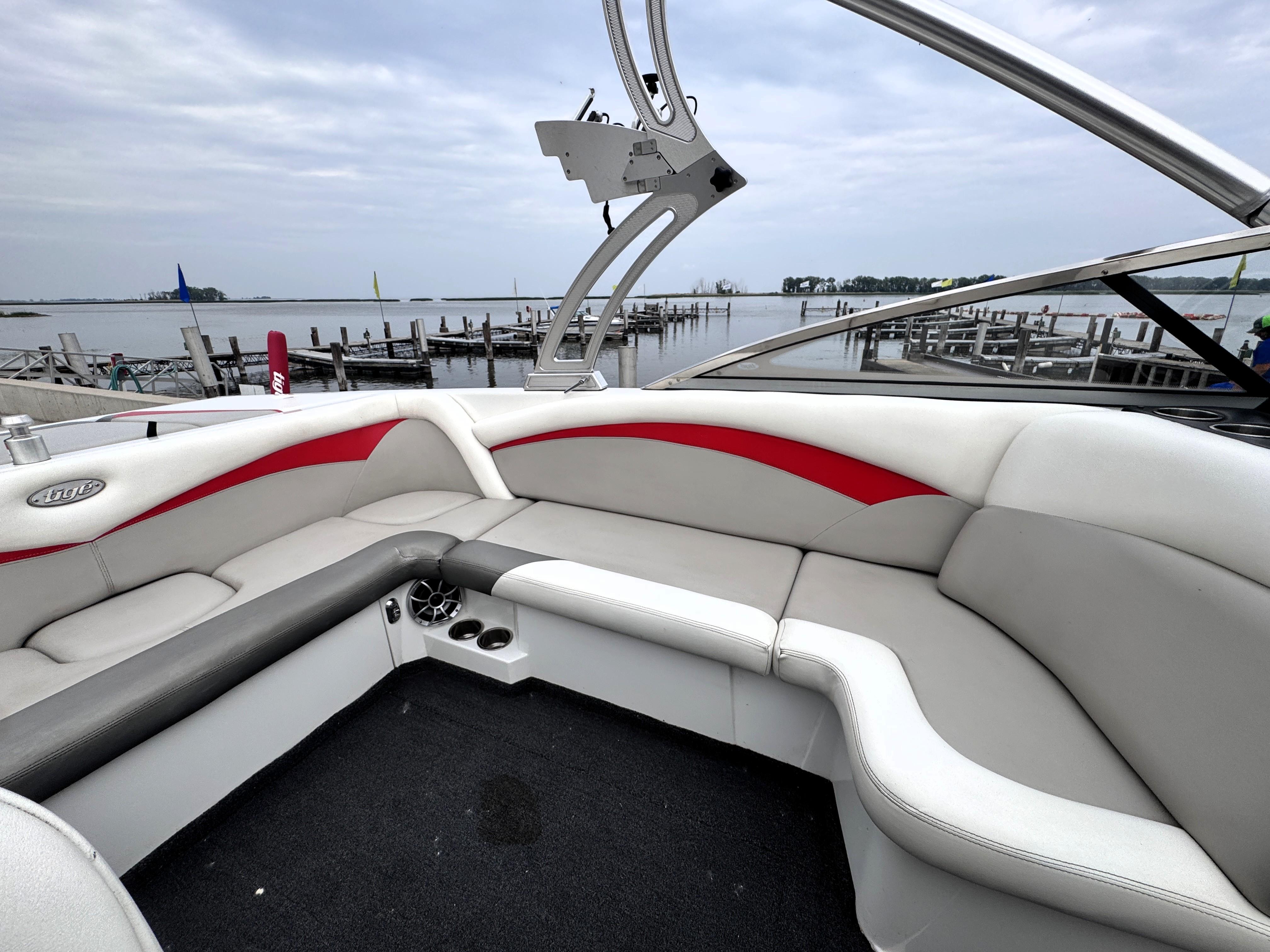 Slide: The Image of 2007 Tigé RZ2 boat interior with red and white seating, docked by a calm lake. - 10