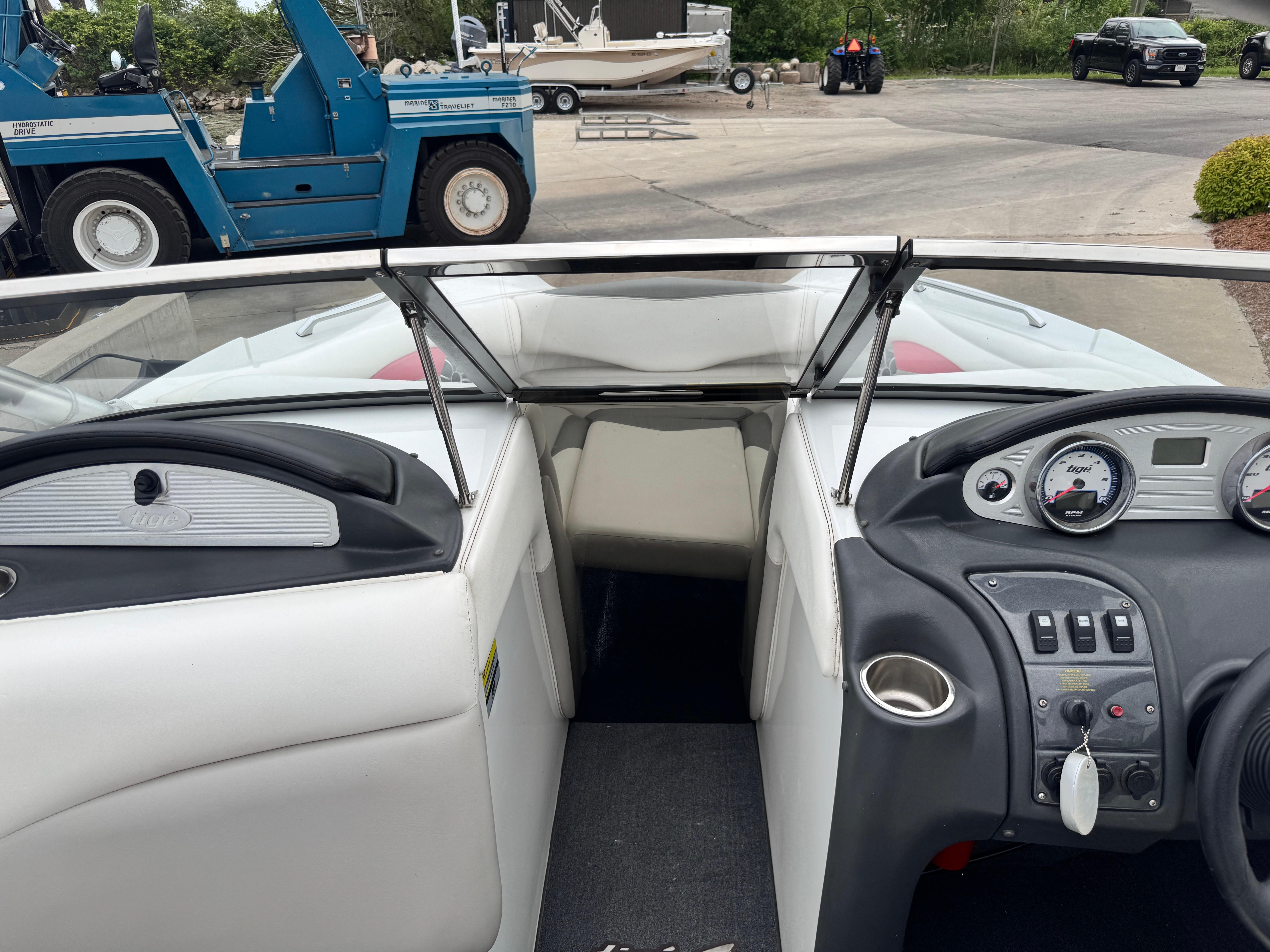 Slide: The Image of 2007 Tigé RZ2 boat interior with dashboard and steering wheel, parked near industrial equipment. - 12