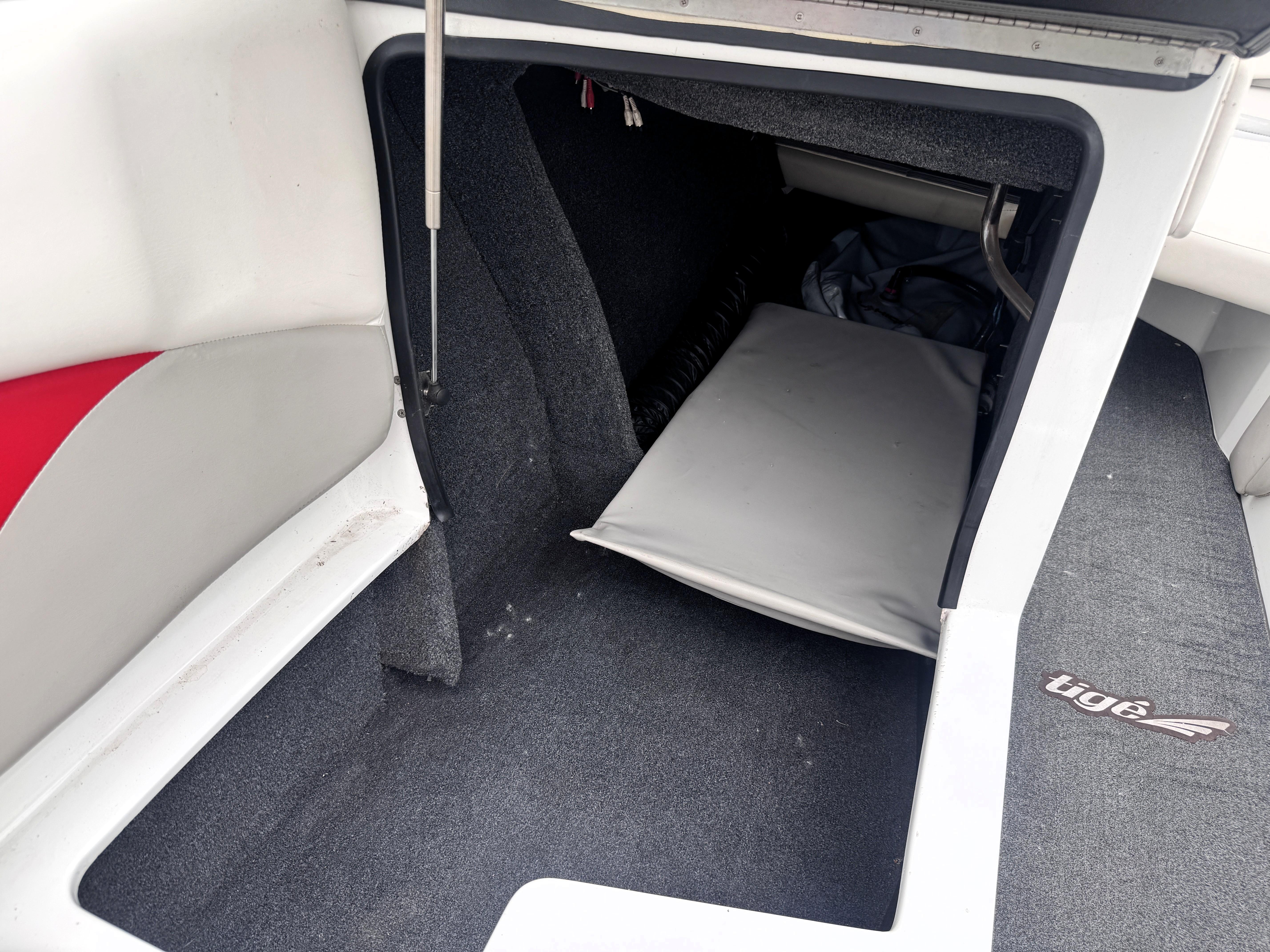 Slide: The Image of Interior storage compartment of a 2007 Tigé RZ2 boat, featuring carpeted flooring. - 13