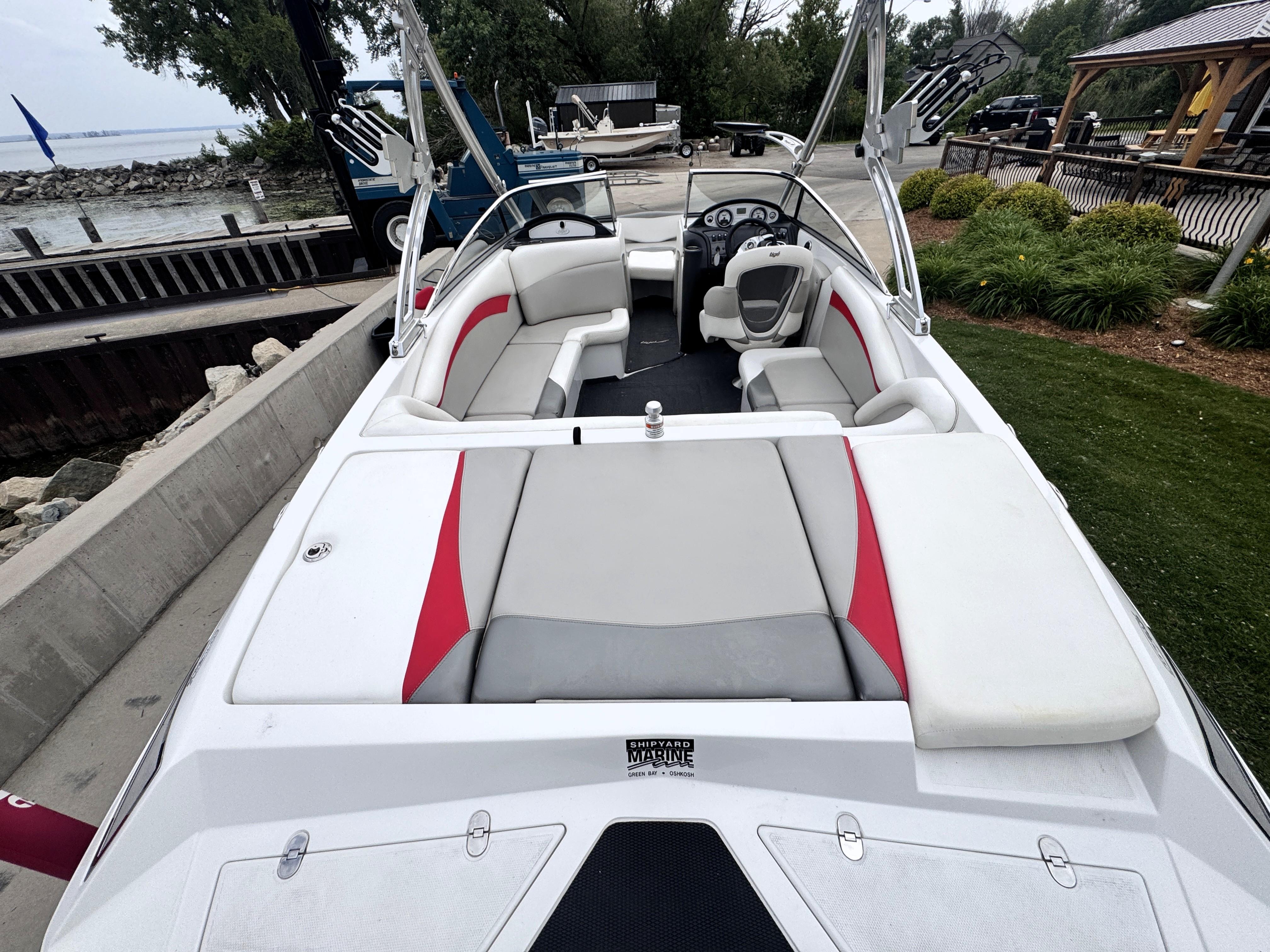 Slide: The Image of 2007 Tigé RZ2 boat interior with red and gray seating, docked near a waterfront. - 17