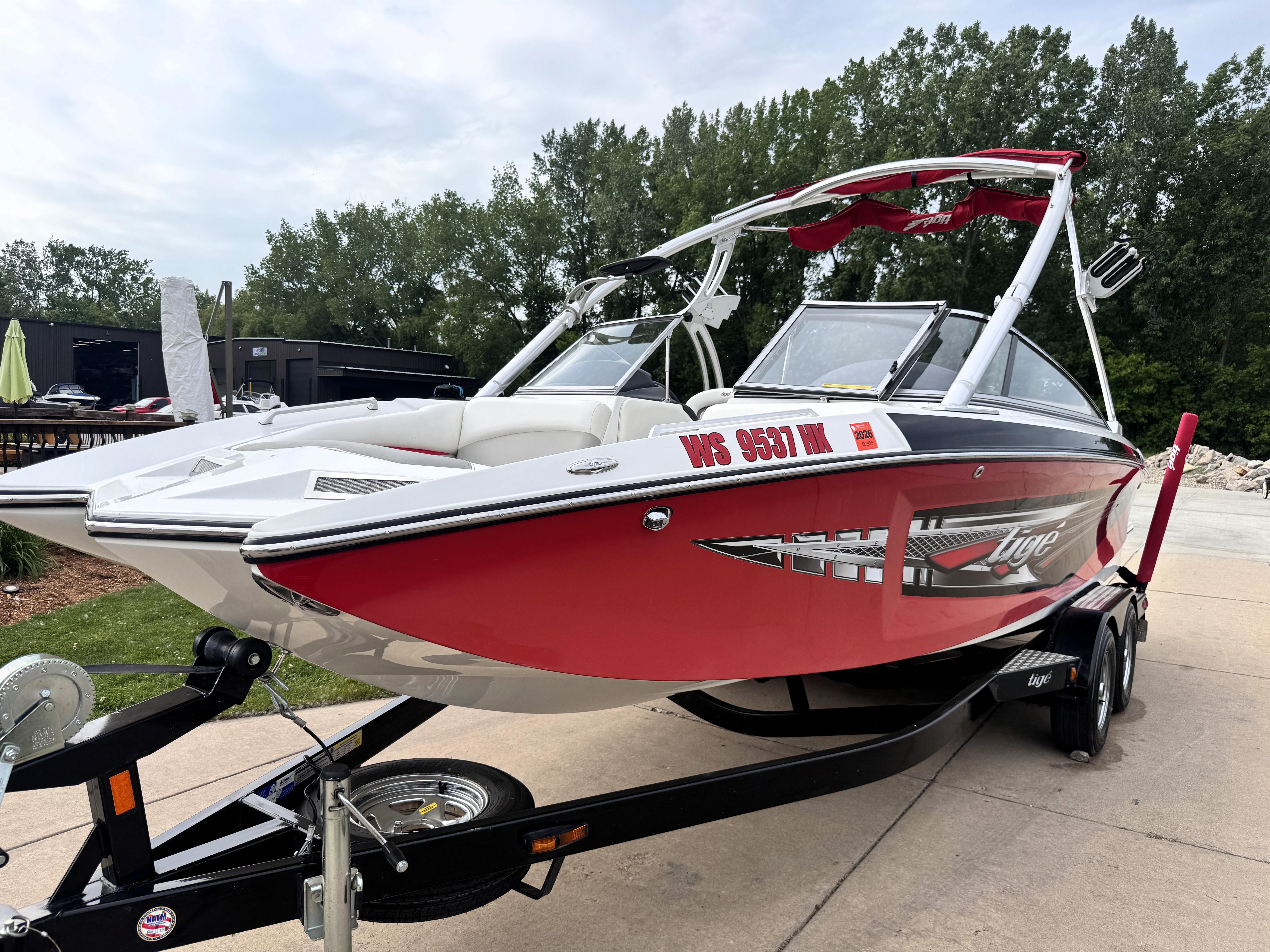 Slide: The Image of 2007 Tigé RZ2 boat on trailer, red and white design, parked outdoors. - 2