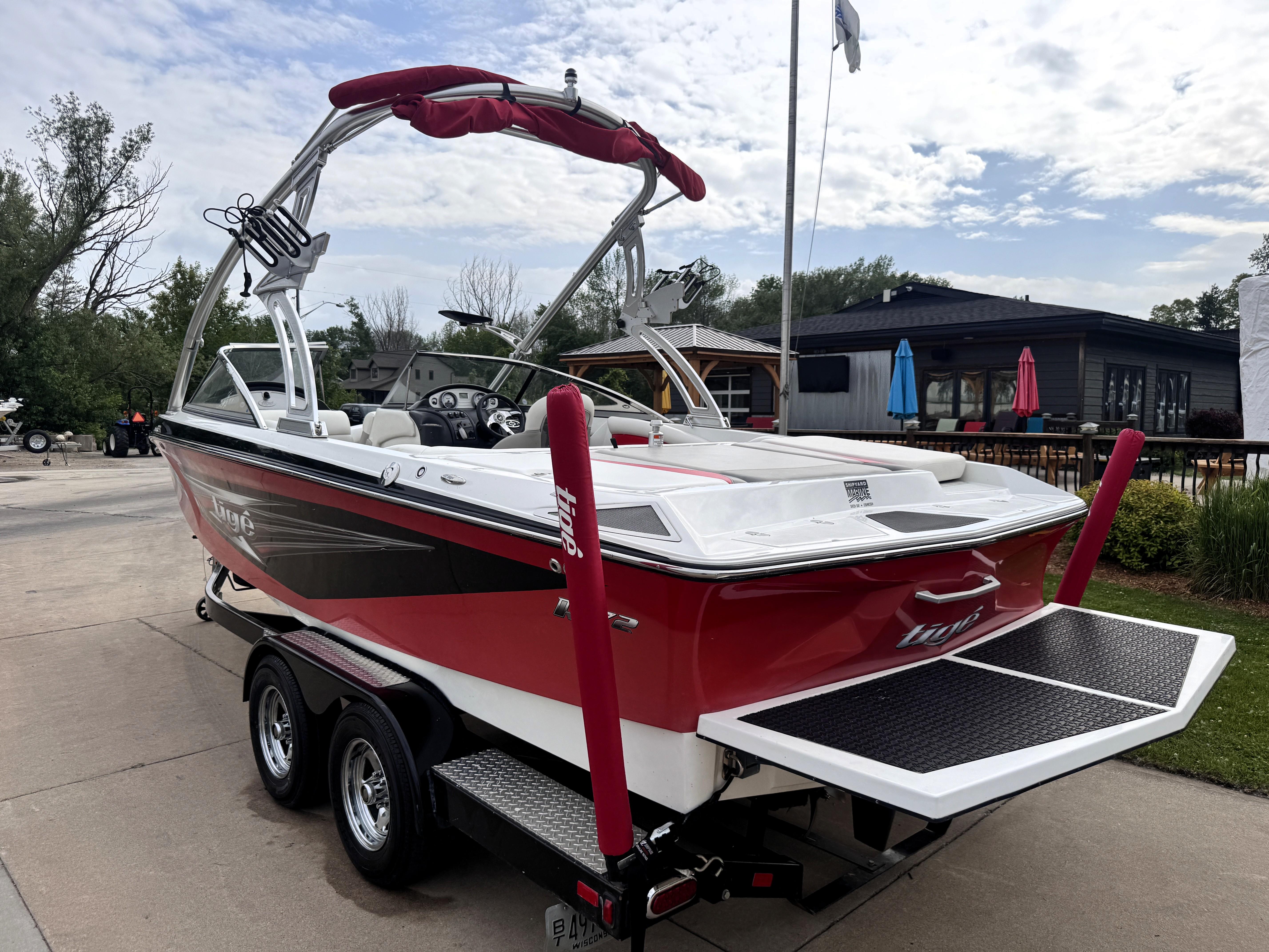 Slide: The Image of 2007 Tigé RZ2 boat on trailer, red and white, parked outdoors under cloudy sky. - 3