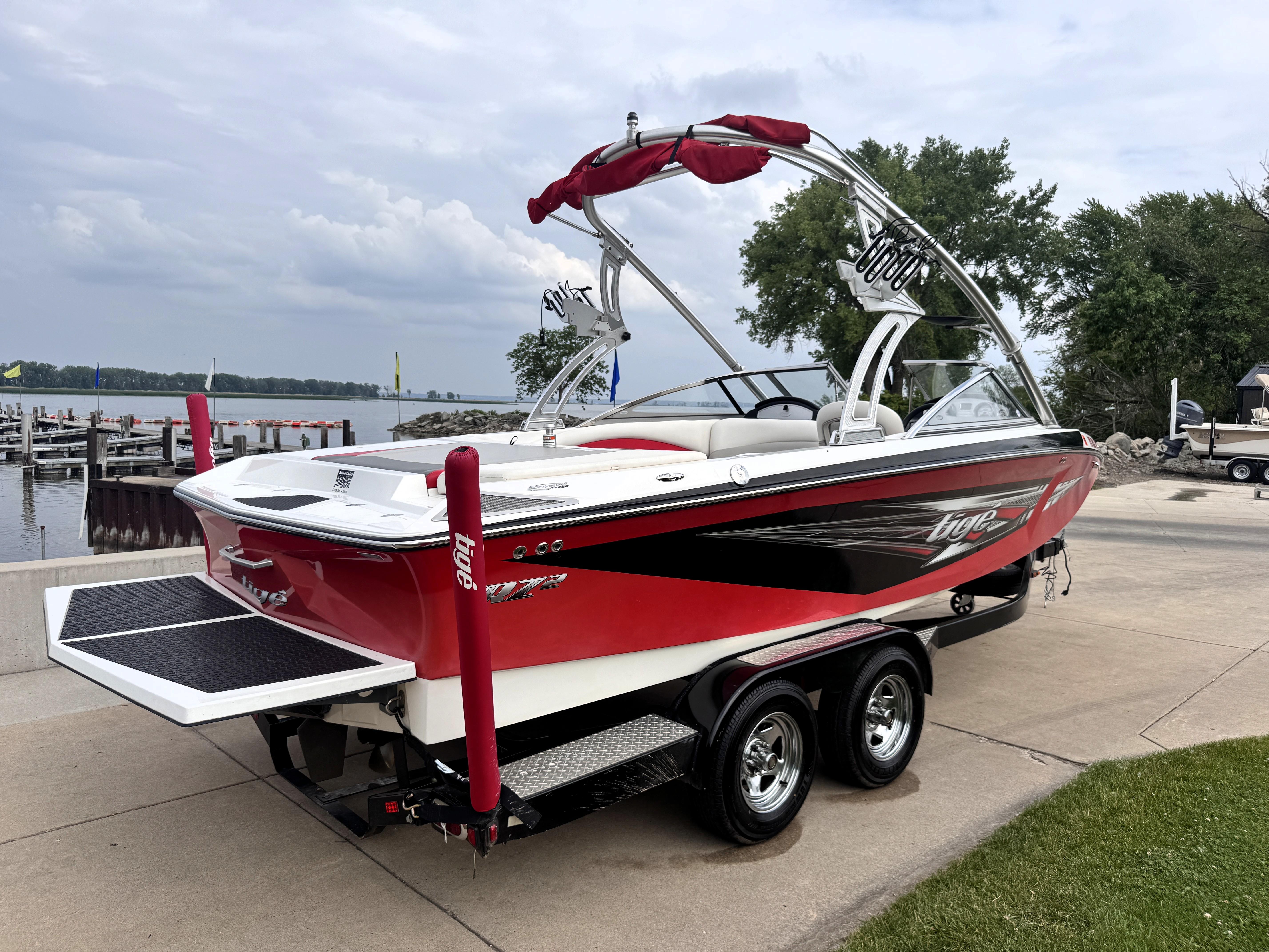 Slide: The Image of 2007 Tigé RZ2 boat on trailer by lakeside, featuring red and black design. - 4