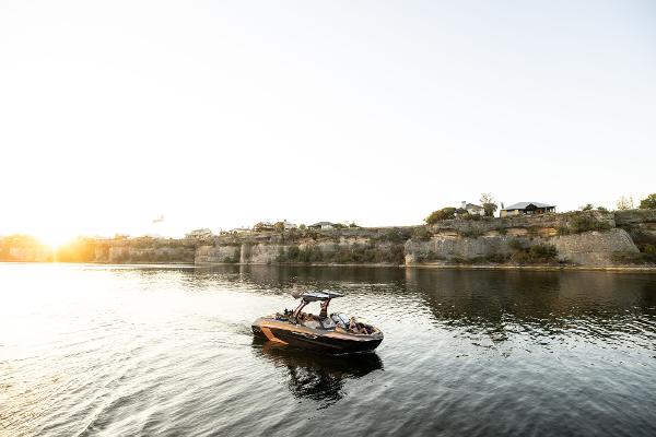 Slide: The Image of 2024 Tigé ULTRA ZX 23 and 25 boat cruising on a serene lake at sunset. - 11