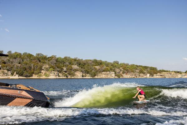 Slide: The Image of 2024 Tigé ULTRA ZX 23 and 25 boat creating waves for a wakeboarder. - 22