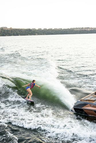 Slide: The Image of Person wakesurfing behind 2024 Tigé ULTRA ZX 23 and 25 boat on a lake. - 23