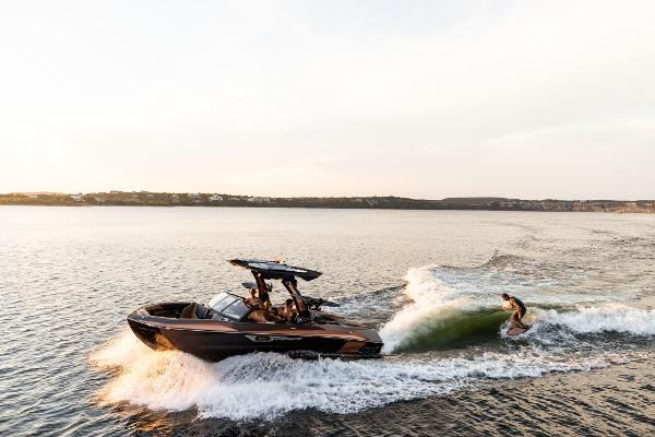 Slide: The Image of 2024 Tigé ULTRA ZX 23 and 25 boat creating waves for a wakeboarder. - 24