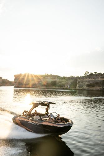 Slide: The Image of 2024 Tigé ULTRA ZX 23 and 25 boat cruising on a lake at sunset. - 25