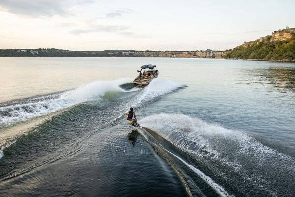 Slide: The Image of 2024 Tigé ULTRA ZX 23 and 25 boat towing a wakeboarder on a serene lake. - 32