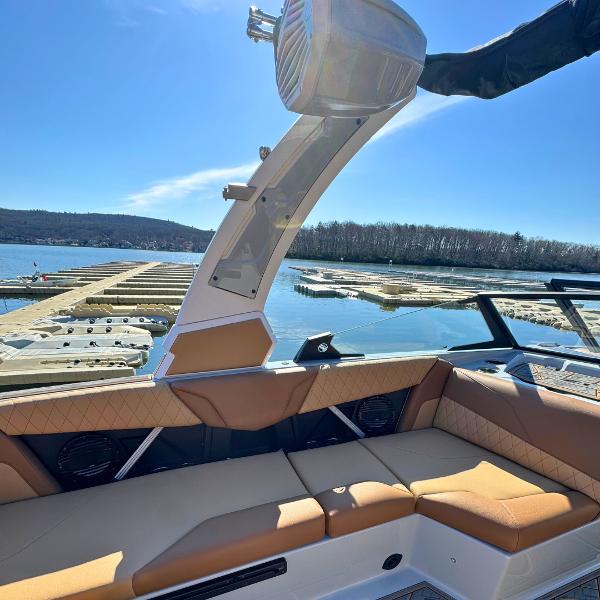 Slide: The Image of 2024 Tigé Z1 boat interior with tan seating at a lakeside dock. - 14