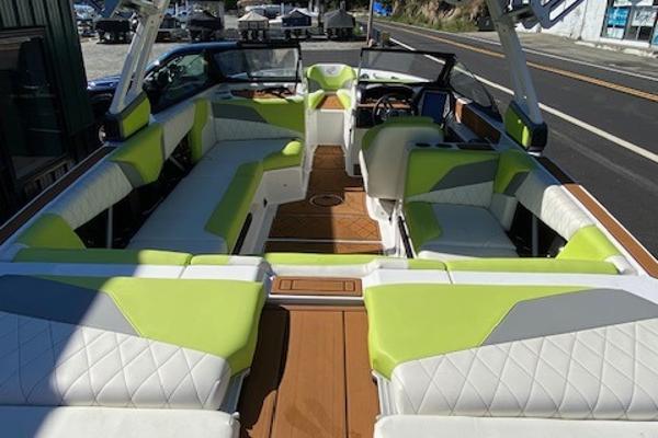 Slide: The Image of 2021 Tigé Z3 boat interior with lime green and white seating, docked near a road. - 12