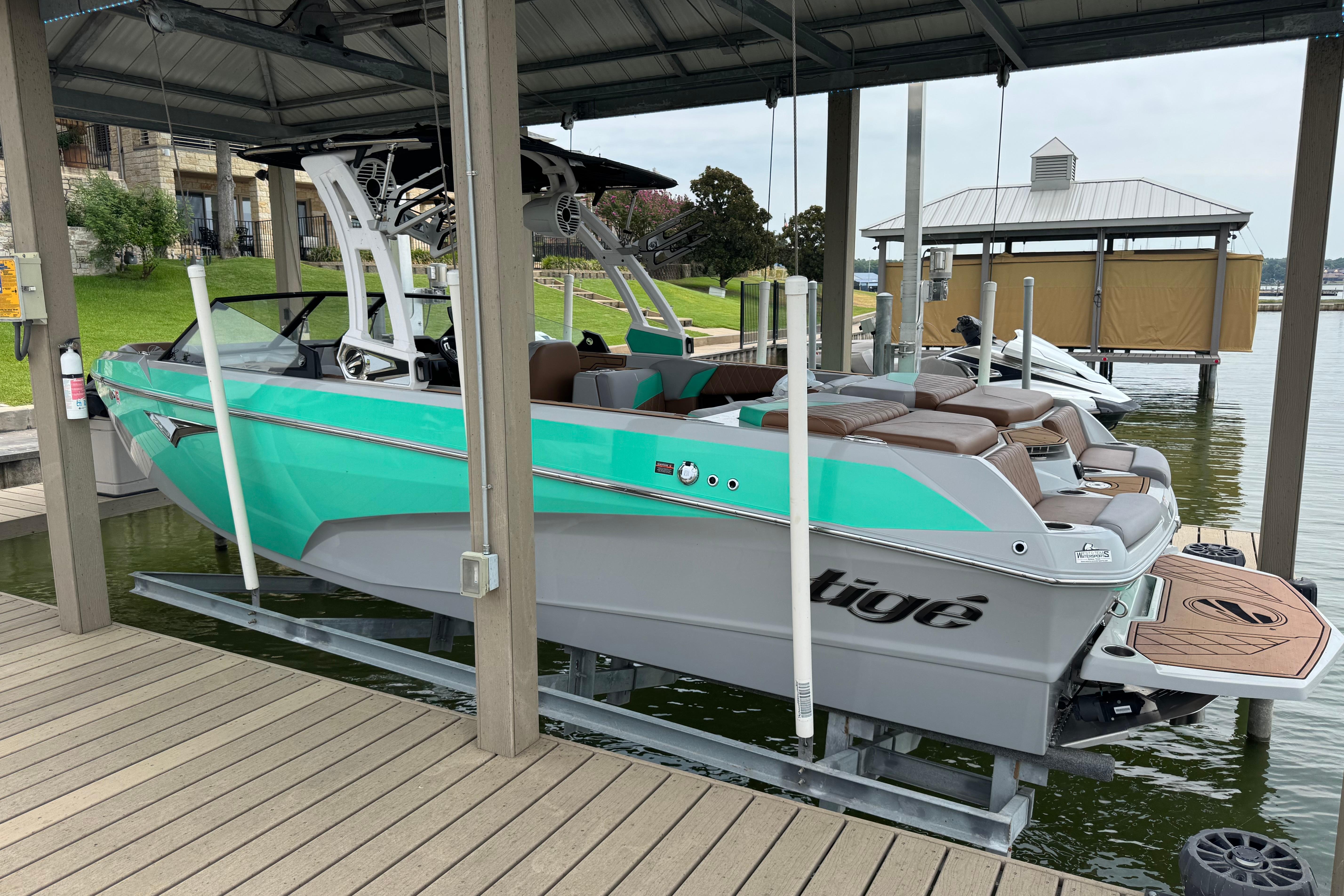 Slide: The Image of 2022 Tigé Z3 boat in turquoise and gray, docked under a covered marina. - 2