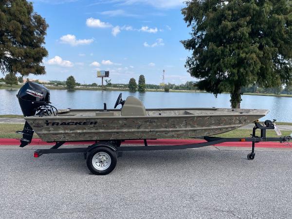 Slide: The Image of 2024 Tracker Grizzly 1648 SC boat on trailer by a lake. - 0