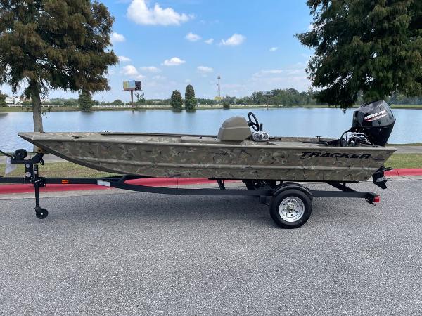 Slide: The Image of 2024 Tracker Grizzly 1648 SC boat on trailer by a lake. - 1