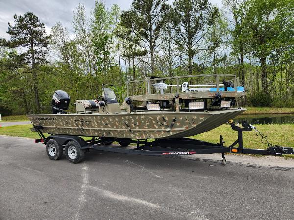 Slide: The Image of 2024 Tracker Grizzly 2072 CC boat on a trailer in a wooded area. - 0