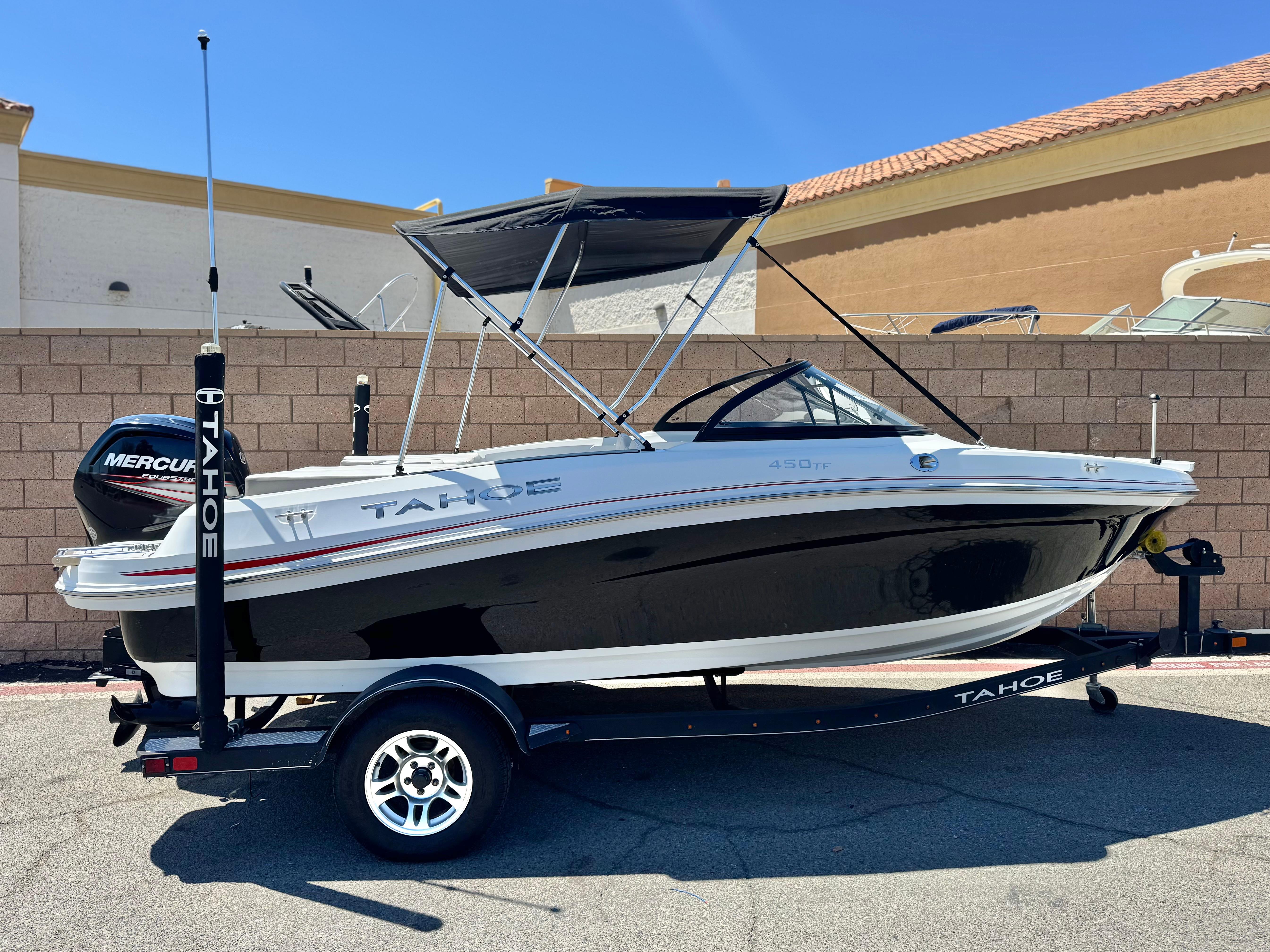 Slide: The Image of 2019 Tracker Tahoe 450 TF boat on trailer, black and white design, parked outdoors. - 0