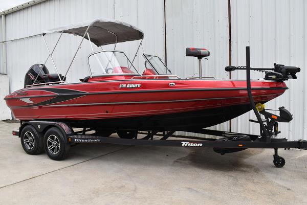 Slide: The Image of 2024 Triton 206 Allure red fishing boat on trailer with canopy. - 0