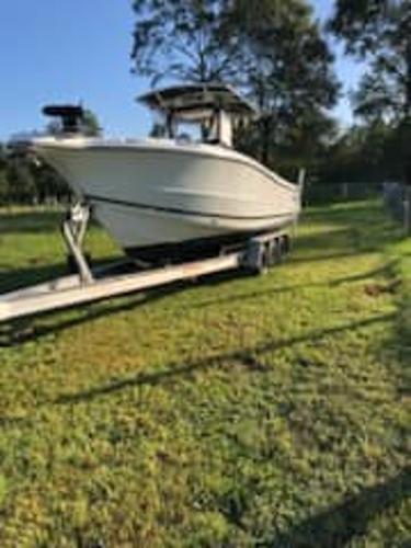 Slide: The Image of 2004 Triton 2690 CC boat on a trailer in a grassy area. - 0