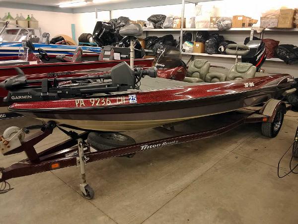 Slide: The Image of 2001 Triton TR186 SC boat in storage, featuring a Garmin system and trailer. - 0