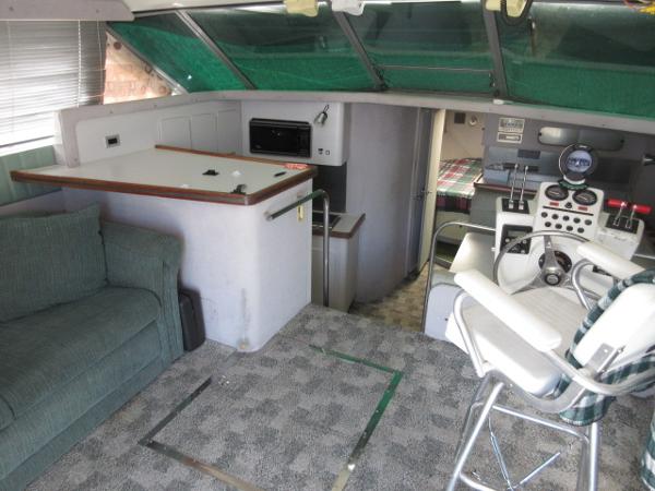 Slide: The Image of 1986 Trojan 11 Meter Convertible interior with helm, seating, and kitchenette. - 13