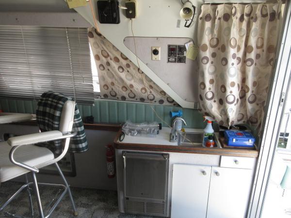 Slide: The Image of Interior of a 1986 Trojan 11 Meter Convertible boat with kitchenette and seating area. - 15