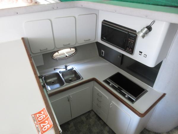 Slide: The Image of 1986 Trojan 11 Meter Convertible boat kitchen with sink, stove, microwave, and cabinets. - 18