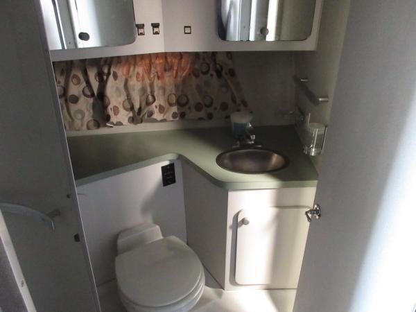 Slide: The Image of 1986 Trojan 11 Meter Convertible boat bathroom with sink, toilet, and storage cabinets. - 23