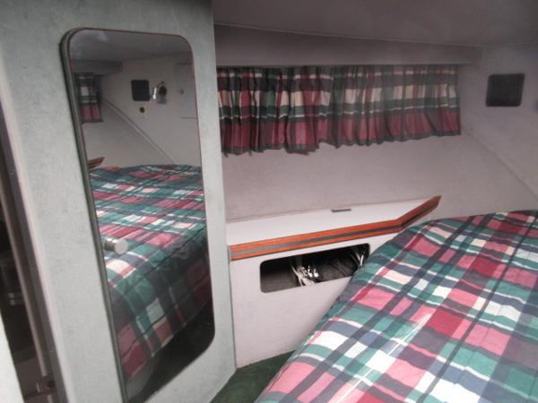 Slide: The Image of 1986 Trojan 11 Meter Convertible cabin with plaid bedding and mirrored closet. - 26
