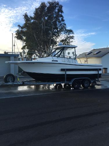Slide: The Image of 2003 Trophy 2052 Walkaround boat on a trailer, parked near houses and trees. - 1