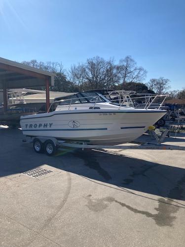 Slide: The Image of 1997 Trophy BAYLINER WALK AROUND boat on a trailer in a marina. - 2