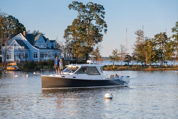 Slide: The Image of 2024 True North 34 boat cruising near a lakeside house with trees in the background. - 21