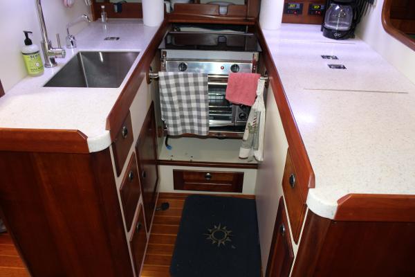 Slide: The Image of Compact kitchen in a 1996 Valiant 42 sailboat with wooden cabinets and modern appliances. - 38