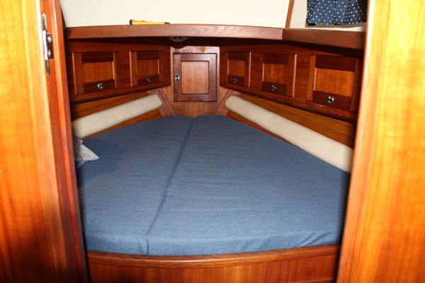Slide: The Image of 1996 Valiant 42 boat cabin with blue bedding and wooden storage cabinets. - 42