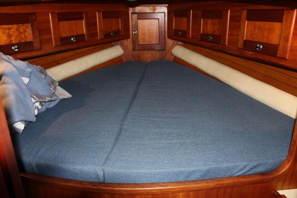 Slide: The Image of Valiant 42 1996 sailboat interior with blue cushioned V-berth and wooden cabinetry. - 43