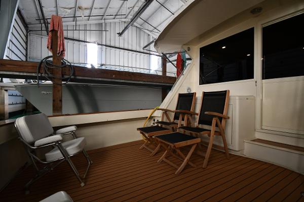 Slide: The Image of 1988 Viking 48 Convertible yacht interior with wooden deck and folding chairs in a boat shed. - 11