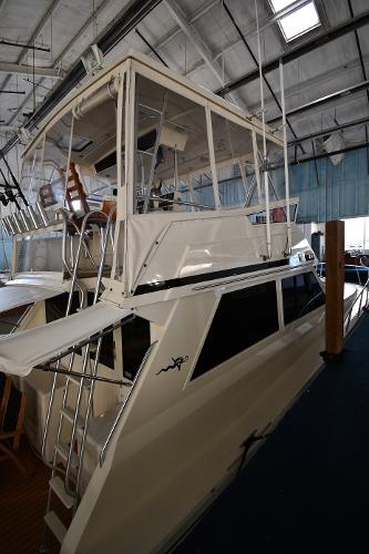 Slide: The Image of 1988 Viking 48 Convertible yacht in a marina, showcasing its sleek design and upper deck. - 2