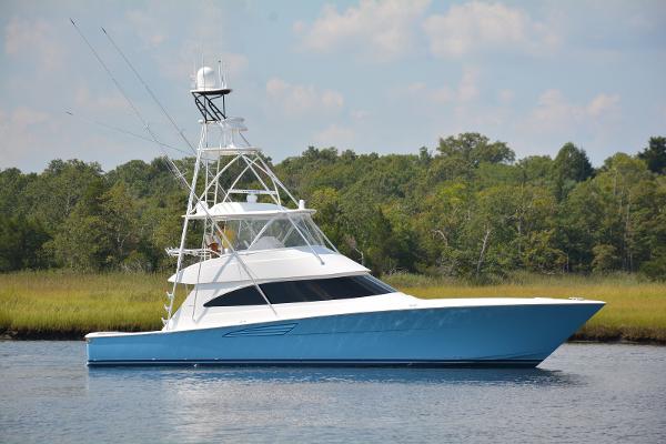 Slide: The Image of 2025 Viking 58 Convertible yacht on calm water with lush green background. - 0