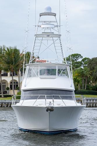 Slide: The Image of 2005 Viking 61 yacht on water, front view, with tower and lush background. - 2