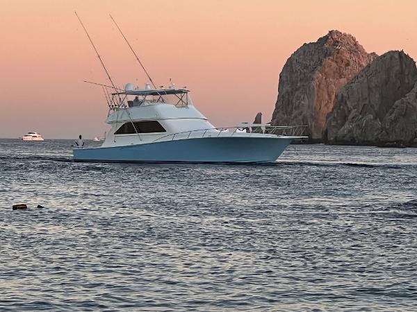 Slide: The Image of Viking 65 Convertible yacht cruising near rocky coastline at sunset, 2000 model. - 6