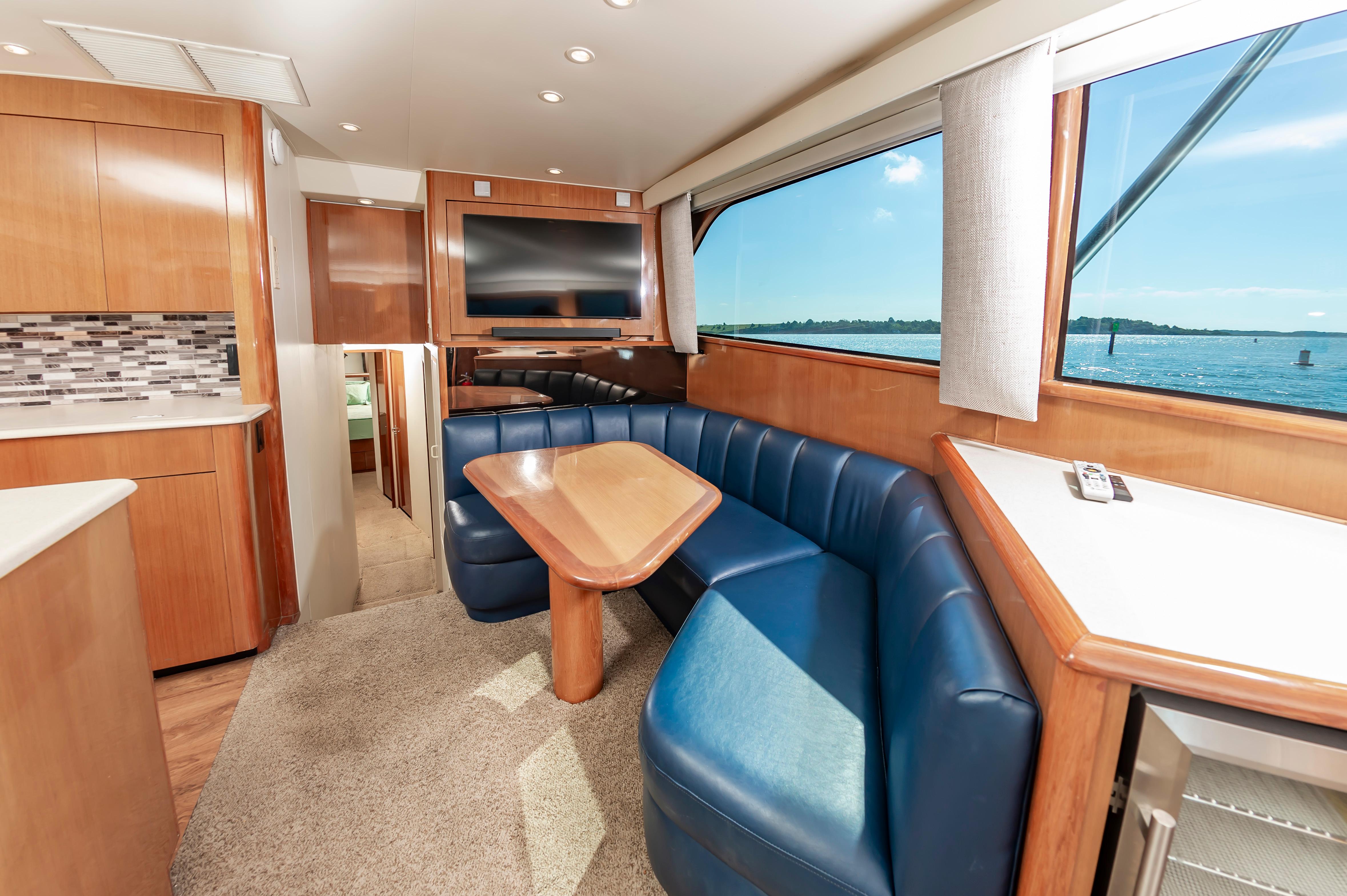 Slide: The Image of Interior of 1998 Viking Convertible yacht with blue seating, wooden table, and large window. - 34