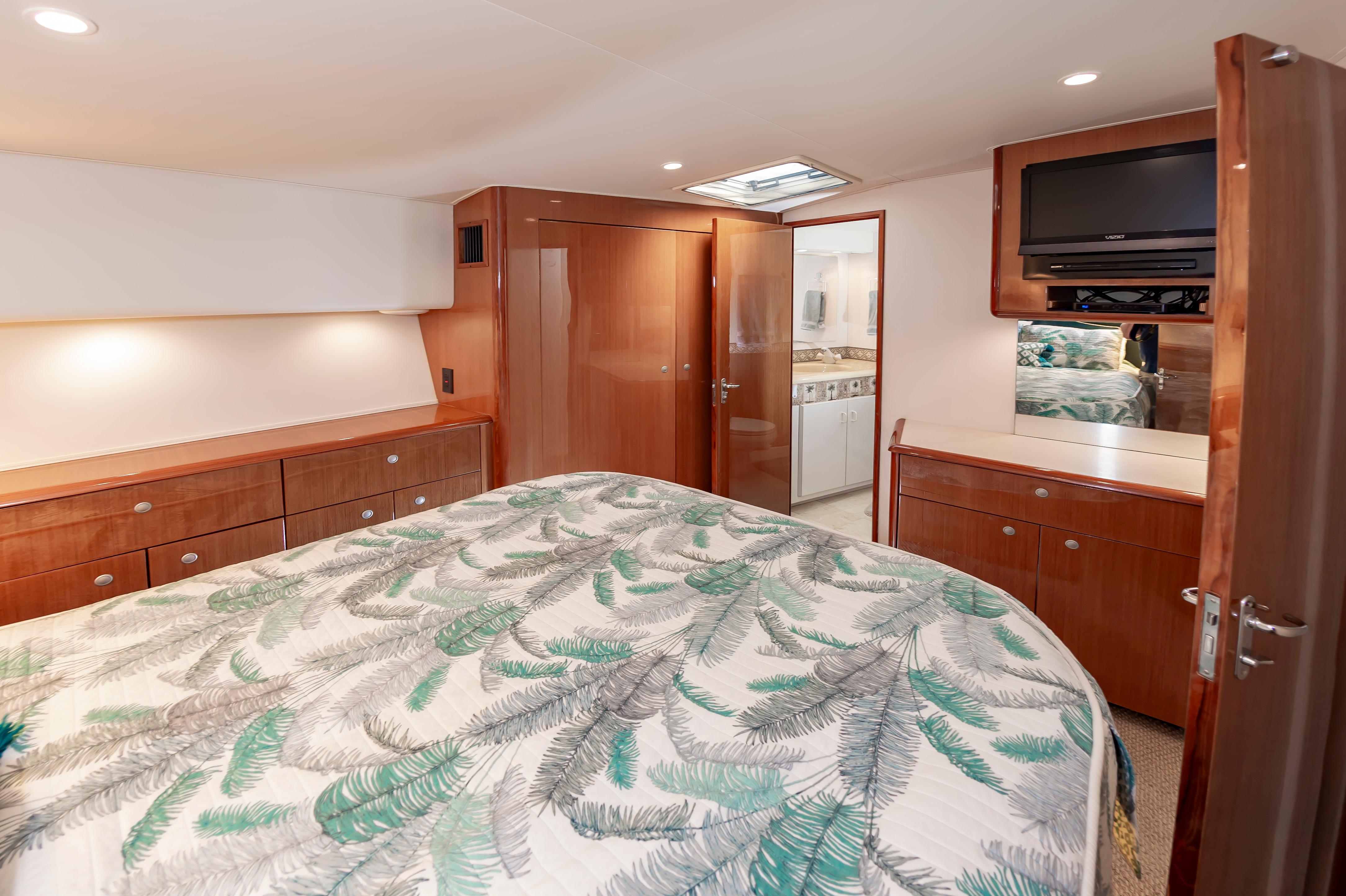 Slide: The Image of 1998 Viking Convertible yacht bedroom with wooden cabinetry, TV, and ensuite bathroom. - 44