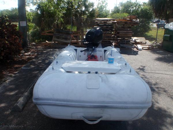 Slide: The Image of 2016 Walker Bay Odyssey 310 SLRX inflatable boat with outboard motor in a yard. - 1