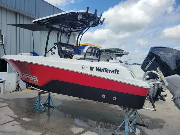 Slide: The Image of 2024 Wellcraft 222 Fisherman boat on stands, red and white hull, Mercury outboard engine. - 1